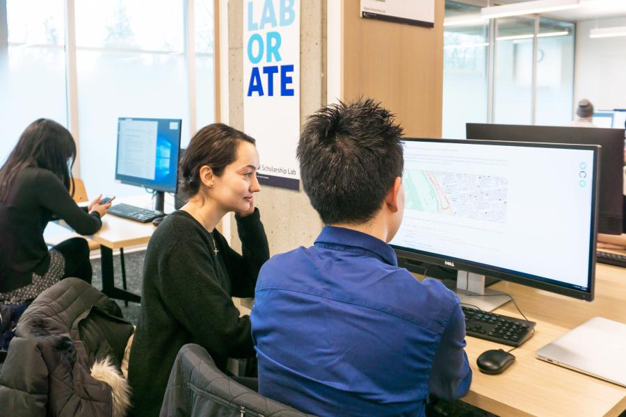 Students sitting in the research commons looking at a computer screen together