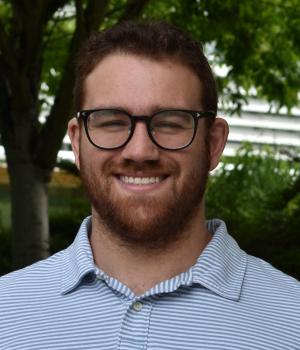 Main with glasses and a beard standing outside