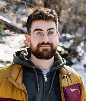 Person with a beard and glasses standing outside with snow in the background