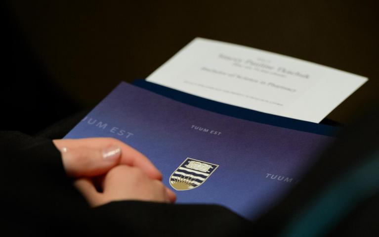 A graduate's hands holding a UBC graduation event program, from the spring 2014 congregation. Photo credit: Don Erhardt / UBC Communications & Marketing