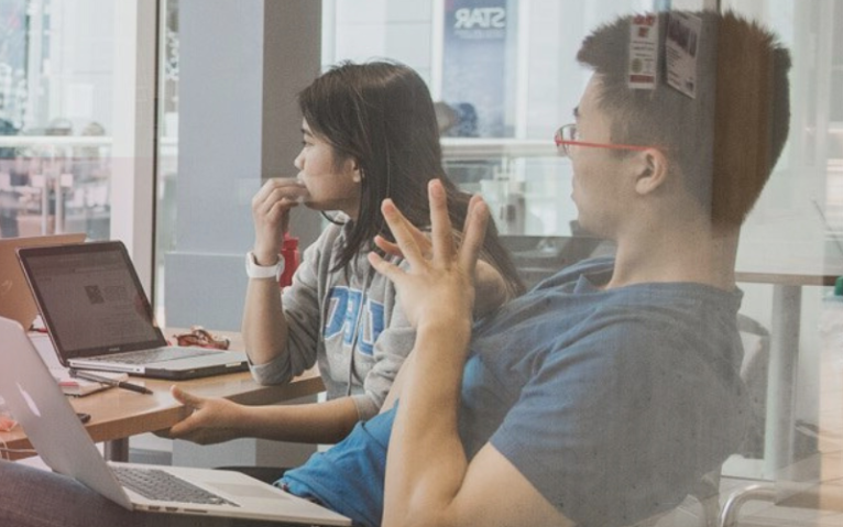 Students sitting around a table with the words We're hiring