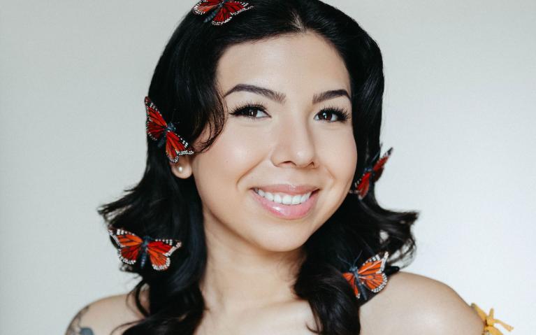 person with dark hair and red butterflie woven into their hair