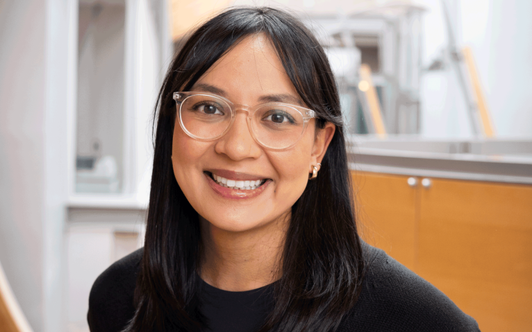 Woman with black shirt and black hair smiling with glasses