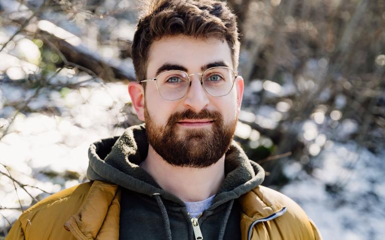 Person with a beard and glasses standing outside with snow in the background