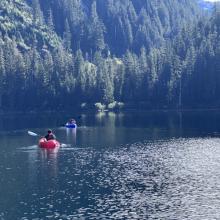Photo of two kayaks on a lake surrounded by evergreen trees