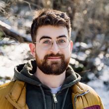 Person with a beard and glasses standing outside with snow in the background