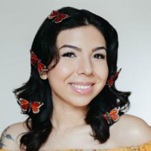 person with dark hair and red butterflie woven into their hair
